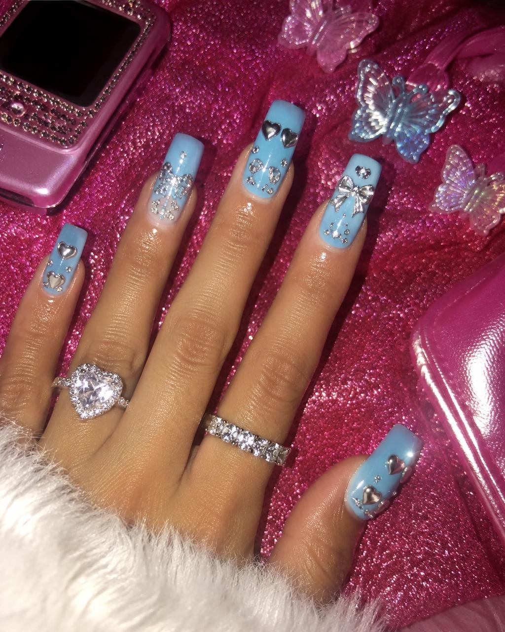 Baby blue square nails with silver chrome hearts and bows on hot pink glitter